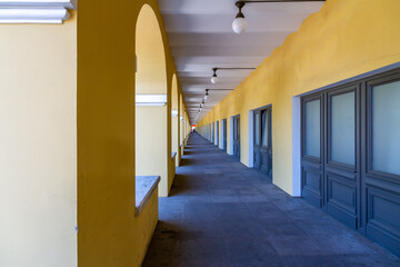 Perspective view of the long arched gallery of Nikolskie Rows with yellow walls and grey doors. Classic architecture and symmetry. Saint Petersburg, Russia