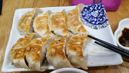 Fried dumplings on a plate with sauce and chopsticks