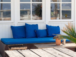 Blue cushioned bench and rustic table at beachside café – perfect for summer dining promo, beach summer walk, dining out in Zandvoort, Netherlands
