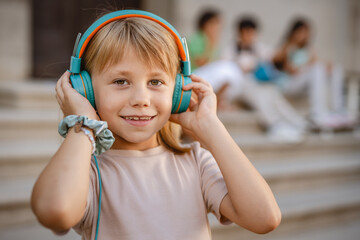 Smiling girl listening to music with headphones outdoors