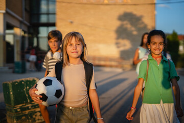 Elementary school students leaving school after class with soccer ball