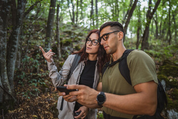 Hikers using smartphone and navigating in forest