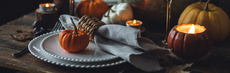 Beautiful seasonal decorated Thanksgiving table for cozy family dinner or fall luxury countryside wedding. Elegant beautiful setting for holiday event, party, reception. Wineglasses and fancy dishes.