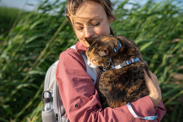 Grumpy curious cat frowns while inspecting grass nature from woman owner arms. Feline curious and...