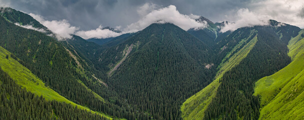 Storm clouds gathering over gorge in Tian Shan, creating a dramatic landscape of green mountains...