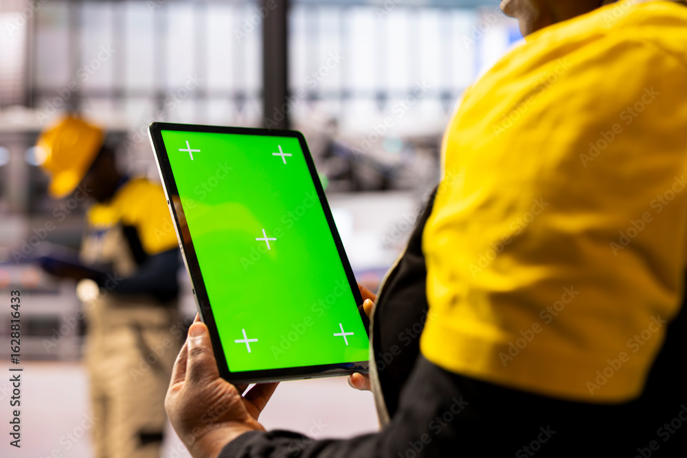 Poster factory manager handling operations as she holds tablet with green screen display. professional indu