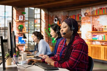 Multiethnic team of call center agents answering clients technical inquiries about hardware issue. Multiracial customer support workers in office doing job using PC to troubleshoot problems