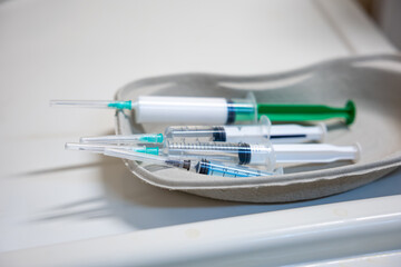 A set of unused syringes with clear barrels and green and white plungers placed in a kidney shaped...