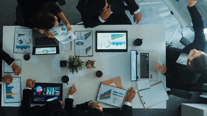 Top down aerial view of smart manager pointing at financial graph on whiteboard while diverse business team explain and plan marketing idea at meeting table with stock market statistic. Directorate. - Powered by Adobe