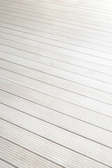 A detailed view of a light colored wooden deck featuring evenly spaced parallel grooves, highlighting its uniform texture and modern design.