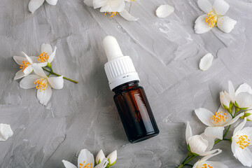 A bottle with cosmetic essential oil and white jasmine blossom. Natural cosmetics, skin care concept. Top view, flat lay
