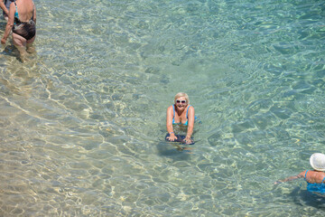 Elderly woman is posing in transparent clear sea water.