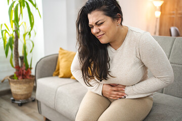 Woman experiencing painful stomachache at home