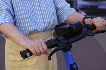 Close-up of a person's hands gripping the handlebars of an electric scooter. The individual is wearing casual attire and appears ready to ride, demonstrating focus and control.
