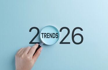 2026 Business Trends Concept. A hand holds magnifying glass focusing on the word Trends within the...