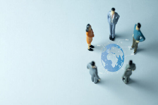 Miniature business people figures in a meeting around a virtual globe. A concept for global business, international strategy, globalization, worldwide teamwork, and corporate management. - Powered by Adobe