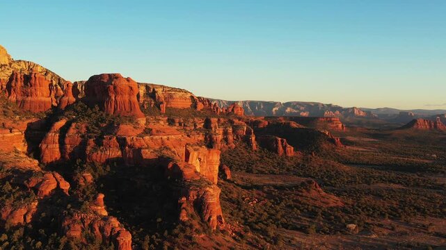 Bear Mountain and red rock formations near Sedona, Arizona glow in the evening sun. Aerial drone shot with dolly-in and boom-up movement.