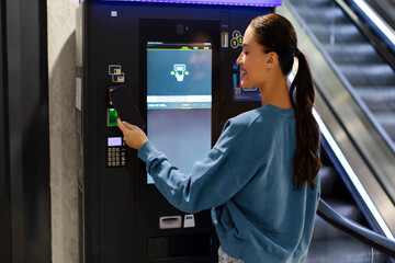 Young woman paying for service underground parking or buying a subway or train ticket using...