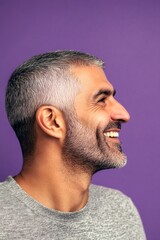 Obraz premium Purple solid background. A joyful male captured in a professional portrait. Trendy men's buzz cut haircut - midlife arabian man with short hair. Idea art of style for aging men.