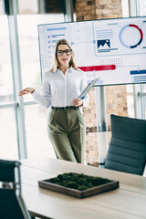 Qualified Businesswoman Presenting Data in a Conference Room with a Modern Screen Display and Professional Attire