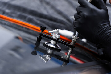 Windshield crack repair using resin injection. Technician using windshield injector tool to fix...