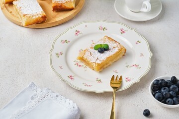 Dessert, lemon cake bar on shortcrust pastry sprinkled with powdered sugar, on a figured dessert...