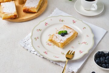 Dessert, lemon cake bar on shortcrust pastry sprinkled with powdered sugar, on a figured dessert...