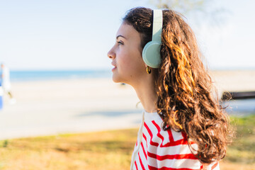 Young woman wearing headphones listening to music by the sea