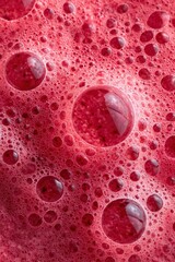 Close-up shows bright red, frothy liquid with varying sizes of bubbles creating a vibrant texture