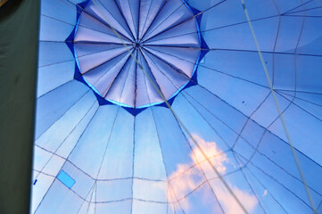 Fototapeta premium View from a hot air balloon basket, looking up at the burner flame heating the blue envelope during flight