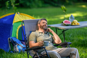 Man drink morning camp coffee in forest. Man hiker relax outdoor. Summer camp and nature vacation....