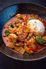 Traditional Thai red curry with king prawns and vegetable - kaeng phet served as top view in a bowl with jasmin rice