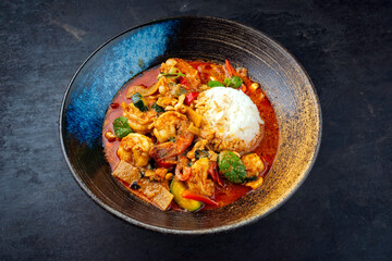 Traditional Thai red curry with king prawns and vegetable - kaeng phet served as top view in a bowl...