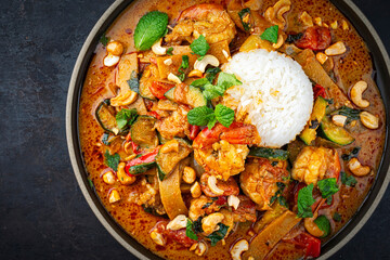 Traditional Thai red curry with king prawns and vegetable - kaeng phet served as as top view in a bowl with jasmin rice