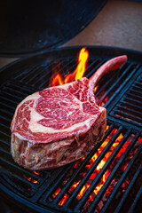 Barbecue dry aged angus tomahawk steak as close-up on a charcoal grill with fire and smoke
