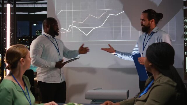 Group of business associates preparing their forecast pitch for a discussion with investors, increasing funds and corporate activity. Experts addressing financial status at night time. Camera A.