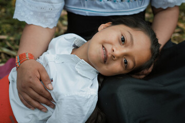 Indigenous girl lying on mother's lap, smiling gently in ecuadorian andes