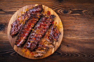 Barbecue smoked hot spicy pork spareribs St Louis cut with curry rub and BBQ sauce on wooden cutting board