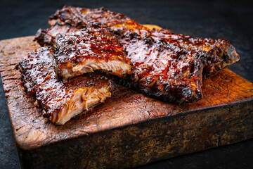 Barbecue smoked hot spicy pork spareribs St Louis cut with curry rub and BBQ sauce on wooden cutting board