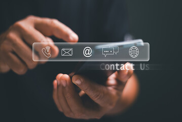 Customer service support concept. Hand using smartphone with virtual contact us interface, showing phone, email, chat and web icons. Representing digital communication. Business connection tools.