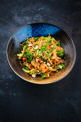 Authentical Thai mie goreng spicy stir-fried noodles with chicken and vegetables served as close-up in a Nordic design bowl