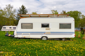 Vintage camper trailers parked by a quiet lakeside camping area in spring. Green grass,...