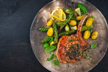 Grilled veal cutlet roast with green asparagus, gnocchi und herbs served as close-up on a rustic design plate