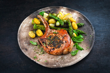 Grilled veal cutlet roast with green asparagus, gnocchi und herbs served as close-up on a rustic plate