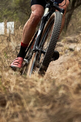 A close-up of a mountain bike in action on rough terrain. The gears and suspension are captured with great clarity, conveying strength, endurance, and adrenaline.