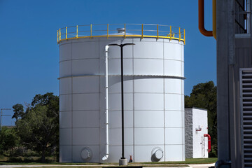 97,000 Gallon Carbon Bolted Steel water Tank, with low Profile Roof and warehouse behind it