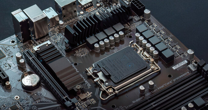 Modern desktop PC motherboard with closed LGA Intel CPU socket cover heatsinks VRM components capacitors, PCI express PCIe RAM slots detailed electronics hardware macro closeup assembly repair concept