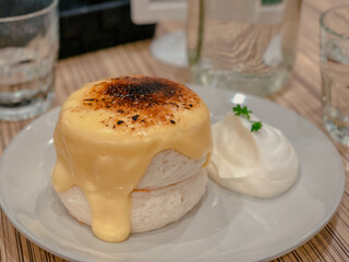 Fluffy Japanese souffle pancake topped with torched cheese and whipped cream on a plate.