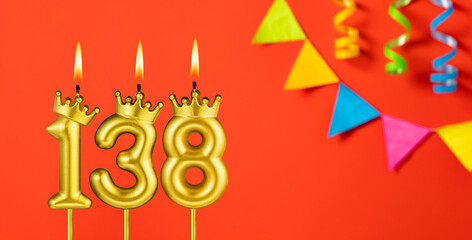 Number 138 birthday candle on an orange background with pennants