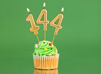 Number 144 birthday candle - Cupcake on a green background